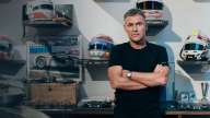Tom Kristensen står foran en væg med en masse hjelme